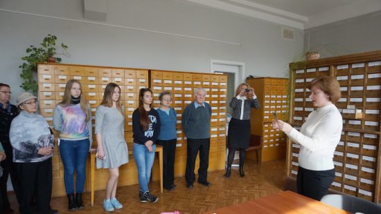 Юні та дорослі учасники семінару слухають розповідь Т. О. Макарової в залі каталогів Центрального державного кінофотофоноархіву України імені Г. С. Пшеничного